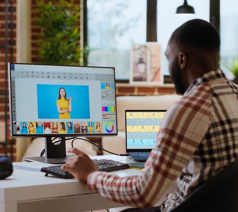 Freelance graphic designer editing photos on a modern computer setup in a remote office. Ideal workspace for a digital design professional, retouching digital pictures from home. Camera B.